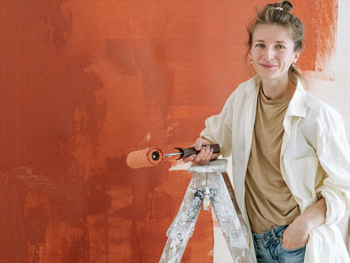 Frau mit Farbroller vor einer terrakottafarbenen Wand